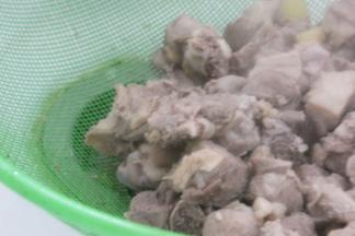 将鸭块捞出，去除葱姜蒜，用温水冲洗鸭块表面的浮沫，沥干水分