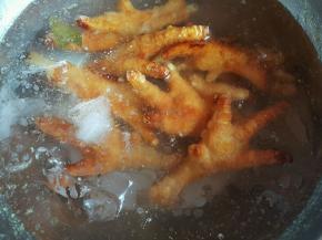 油锅中捞出鸡爪，放入冰水中泡发3小时，泡的鸡爪出虎皮就可以了