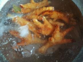 油锅中捞出鸡爪，放入冰水中泡发3小时，泡的鸡爪出虎皮就可以了