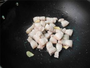 锅中加适量油烧热，放入焯过水的五花肉和姜片煸炒至出油