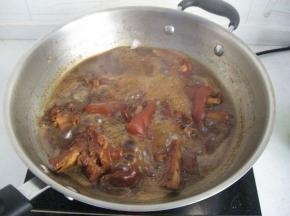 热锅炒冰糖加猪脚上色，倒入姜丝、适量料酒、生抽、老抽等，加水小火焖煮1-2小时