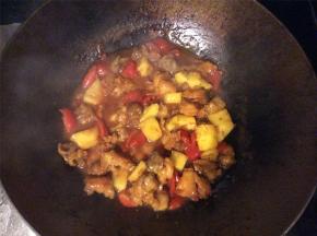 把菠萝块和圣女果倒入酱汁中翻炒，炸好的肉块也放入，保证每块五花肉都包裹上酱汁，翻炒均匀后出锅