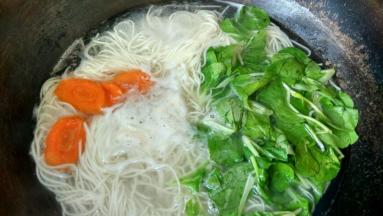 煮开后加少量的冷水，再次煮开时加胡萝卜片和青菜，煮2分钟关火