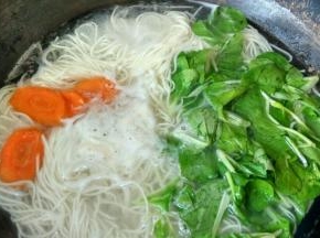 煮开后加少量的冷水，再次煮开时加胡萝卜片和青菜，煮2分钟关火