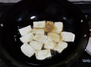 锅中热油，放豆腐片入锅煎，煎成金黄后翻面