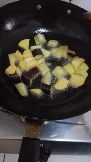 锅内放入比炒菜多一些的油，油温七分热的时候放入土豆和茄子煎一下