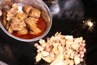 热过入油，小火爆香辅料，加入冬笋和猪蹄、花生翻炒5分钟。