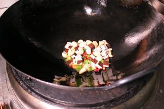 更换油锅，加青椒、干辣椒、豆干粒、姜蒜、爆香，用自制的红油、料酒、盐等调味。