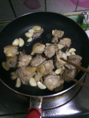 鸡腿肉煸至变色加入蒜瓣，继续煸炒至肉断生