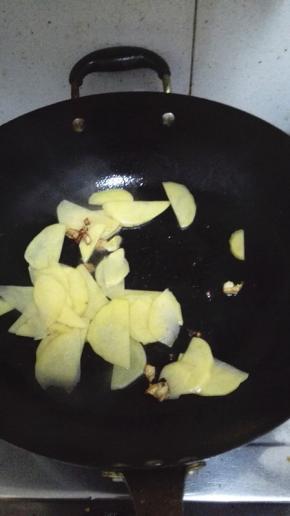 加入土豆片翻炒，炒至土豆片逐渐透明