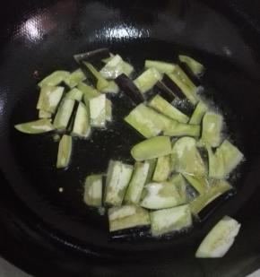 锅内放入比平时炒菜多一些的油，油温七分热的时候放入茄子煸炒