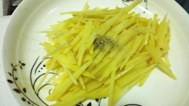 切好的土豆丝放入适量的胡椒粉和盐，搅拌均匀