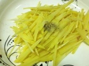 切好的土豆丝放入适量的胡椒粉和盐，搅拌均匀