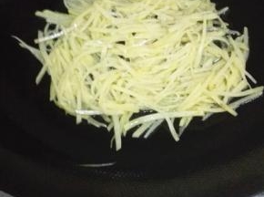 锅内放入少量的油，油热放入土豆丝，用铲子压成饼的形状