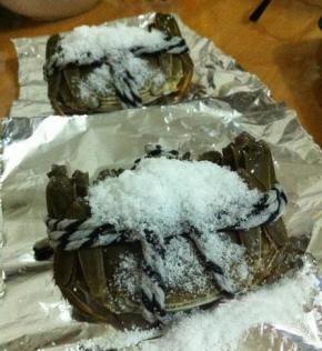 将锡纸扯成长方形，放上大闸蟹，表面上裹上盐