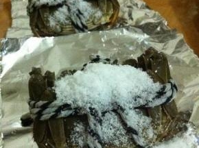 将锡纸扯成长方形，放上大闸蟹，表面上裹上盐