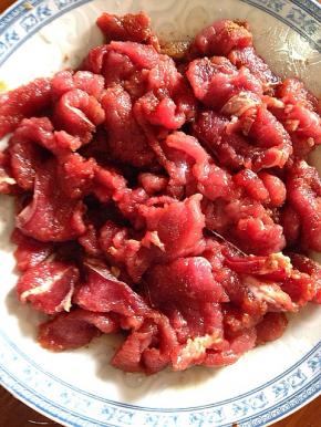 切好的牛里脊放料酒，五香粉，葱蒜腌制半个小时