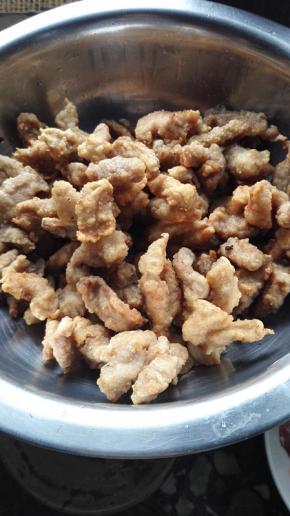 大火将油烧热，放入炸过的猪肉在炸1分钟捞出备用