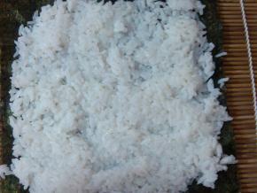 海苔上铺上米饭，用手压平，注意留前端1/4不要铺米