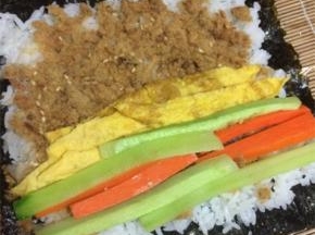 在米饭上依次摆放黄瓜条，胡萝卜条，蛋皮和肉松
