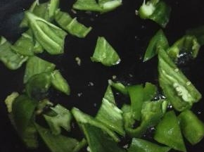 用锅内的余油翻炒青椒，炒至表皮出现褶皱的时候放入煎好的鸡蛋