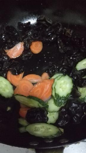 锅内放少许的油，油热之后放入胡萝卜，黄瓜和木耳翻炒至断生