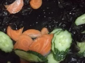 锅内放少许的油，油热之后放入胡萝卜，黄瓜和木耳翻炒至断生