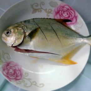 鲳鱼洗净后在鱼身两面划花刀，将处理好的鱼放在碗中，加葱、姜，盐和酒抓匀腌10-15分钟