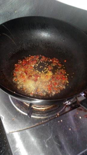 油锅烧热倒入鲜红椒、大蒜、小米辣、姜丝、花椒粒炝香