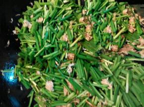 放入韭菜中比较难熟的部分，中火炒软，再将韭菜叶全部放入，炒至变软