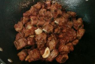 放入排骨，八角，蒜瓣和姜片，倒入生抽，炒至排骨均匀上色
