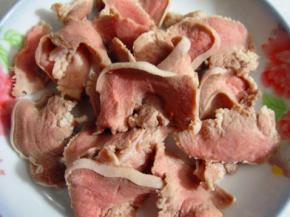 猪舌洗净下水入锅焯一遍，趁热用刀把猪舌头上面的白色粘膜刮除，洗净切片备用