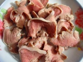 猪舌洗净下水入锅焯一遍，趁热用刀把猪舌头上面的白色粘膜刮除，洗净切片备用