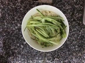 把冷却后的面条放入小碗里，码上切成丝的黄瓜