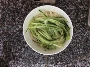 把冷却后的面条放入小碗里，码上切成丝的黄瓜