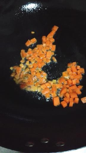 锅内留底油，放入胡萝卜和豌豆翻炒至变软
