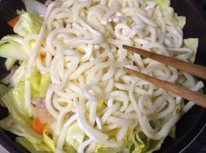 倒入乌冬面，转小火翻炒，加蚝油、酱油、白糖和鸡精调味，炒匀炒熟后出锅