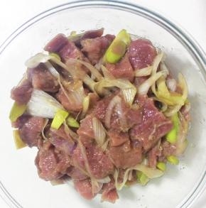 羊腿肉放入碗中，撒上少量的葱段。倒入料酒，胡椒粉，盐和糖，搅拌均匀腌制30分钟