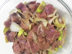 羊腿肉放入碗中，撒上少量的葱段。倒入料酒，胡椒粉，盐和糖，搅拌均匀腌制30分钟