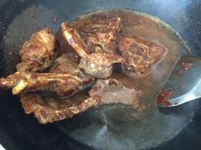 羊蝎子入锅，倒入生抽，料酒和老抽翻炒至均匀上色