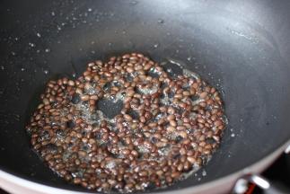 锅中少水，加白糖翻炒糖融放红豆