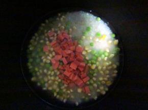 将大米、玉米粒、豌豆、火腿肠粒放入电饭锅中