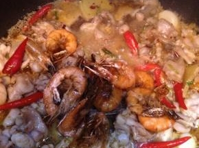 放入小红尖椒，2-3勺辣椒油和花椒油，放入煎好的虾。翻炒，盖上锅盖焖3-5分钟，使其浸入汤汁中充分吸收佐料