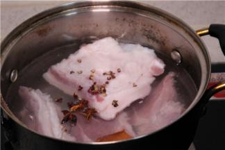 准备一锅冷水，把带皮五花肉放进锅里开火煮，水开后放少许生姜、花椒、八角煮。