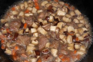 倒入香菇和胡萝卜丁，加酱油、老抽、蚝油和盐翻炒上色，倒入清水没过排骨，大火煮开，小火收汁