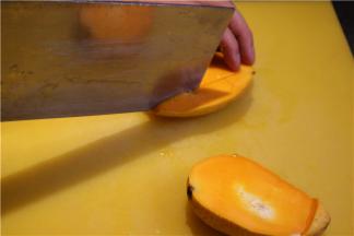 先把芒果切成两半，用刀在芒果果肉上划成9宫格，然后把果皮翻转，用刀切掉果皮。