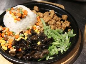 铁板放火上，先开小火，上面码上鸡脯肉。米饭装碗，压实，扣在铁板上。上面再点缀青豆、玉米粒、胡萝卜片。