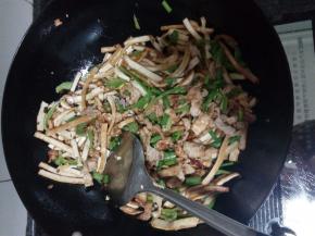 用锅中剩余的油炒豆干和青椒，炒断生后放入肉丝同炒，加少许的盐调味，炒匀出锅