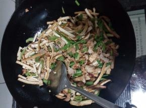 用锅中剩余的油炒豆干和青椒，炒断生后放入肉丝同炒，加少许的盐调味，炒匀出锅