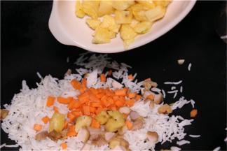 拿出隔夜饭，放入热好的油锅中翻炒，依次加入鸡肉粒、胡萝卜丁、最后倒入菠萝丁翻炒。